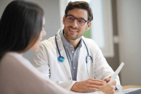 Modern young doctor speaking to patient in office